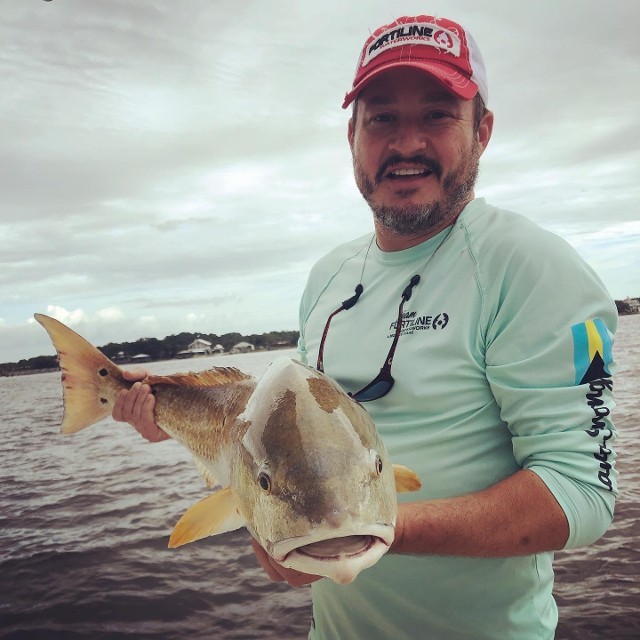 Man In Red Cap Holding A Fish On Filtered Image