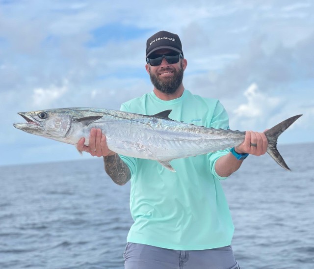 Man In Teal Shirt Holding A Big Fish