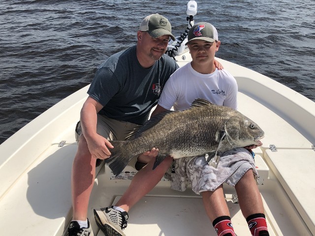 Father And Son Holding A Big Fish