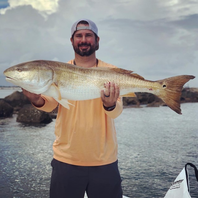 Man In Orange Shirt Holding A Big Fish