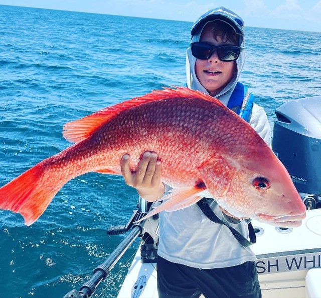 Young Boy In Hoodie Holding An Orange Fish