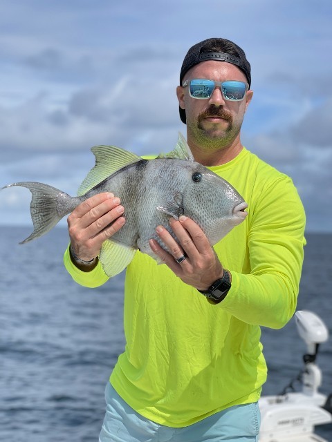 Man In Green Shirt Holding A Fish